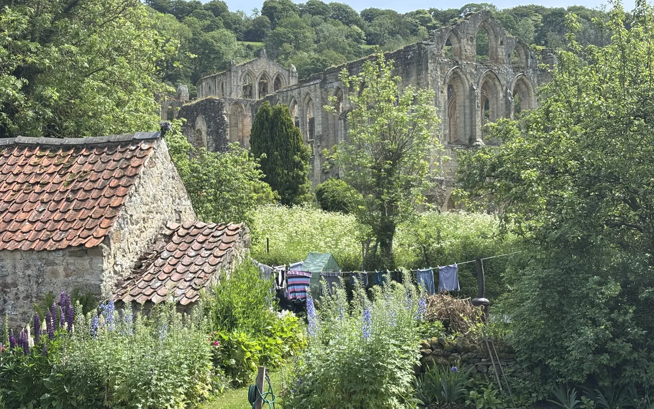 Stone cottage and lush garden beside abbey ruins in Herriot country on the All Creatures and Herriot tour